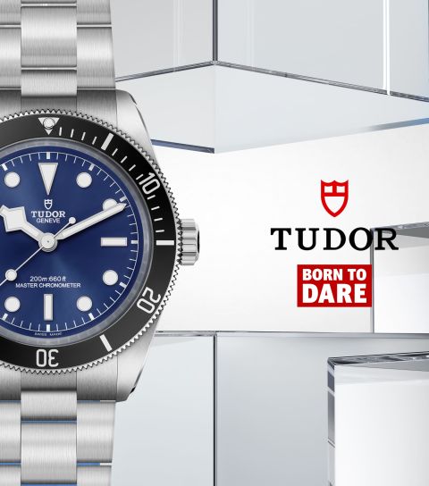 Links Tudor Black Bay 68 Uhr in Stahl mit schwarzer Luenette und blauem Zifferblatt, rechts daneben TUDOR Logo und Born to dare Icon vor blau-grauem Lifestylehintergrund