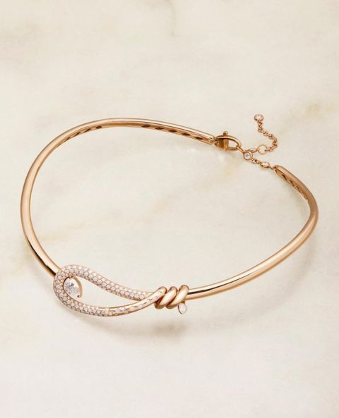 Ros&eacute;goldenes Collier aus der Closer Kollektion von Crivelli mit geschwungenem, diamantbesetztem Zierelement und feiner Knotenform, elegant inszeniert auf hellem Natursteinhintergrund