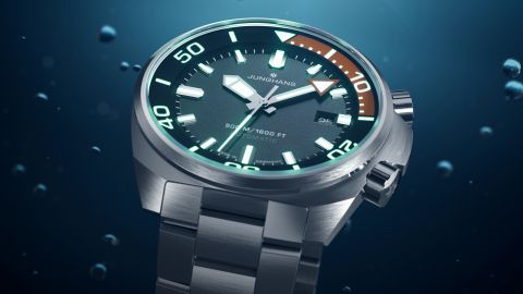 Junghans Aquaris Diver Taucheruhr aus Edelstahl mit dunkelgrauem Zifferblatt und innenliegendem Drehring vor blauem Unterwasser-Hintergrund. Junghans Aquaris Diver Taucheruhr aus Edelstahl mit dunkelgrauem Zifferblatt und innenliegendem Drehring vor blauem Unterwasser-Hintergrund.