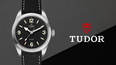 TUDOR Ranger Uhr in Stahl mit schwarzem Zifferblatt auf grau-schwarzem Hintergrund mit TUDOR Logo rechts TUDOR Ranger Uhr in Stahl mit schwarzem Zifferblatt auf grau-schwarzem Hintergrund mit TUDOR Logo rechts