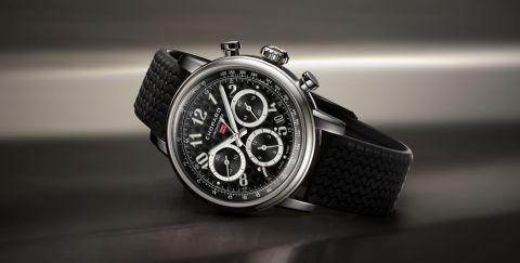 Chopard Mille Miglia Chronograph mit Gehaeuse aus Stahl, schwarzem Zifferblatt mit arabischen Ziffern und schwarzem Kautschukarmband seiltich liegend vor dunklem Hintergrund Chopard Mille Miglia Chronograph mit Gehaeuse aus Stahl, schwarzem Zifferblatt mit arabischen Ziffern und schwarzem Kautschukarmband seiltich liegend vor dunklem Hintergrund