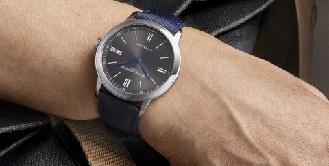 Baume & Mercier Classima Uhr in Stahl mit grauem Zifferblatt und blauem Textilband an einem Herrenhandgelenk getragen Baume & Mercier Classima Uhr in Stahl mit grauem Zifferblatt und blauem Textilband an einem Herrenhandgelenk getragen