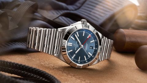Breitling Chronomat Uhr in Stahl mit blauem Zifferblatt seitlich auf Stoffuntergrund liegend Breitling Chronomat Uhr in Stahl mit blauem Zifferblatt seitlich auf Stoffuntergrund liegend