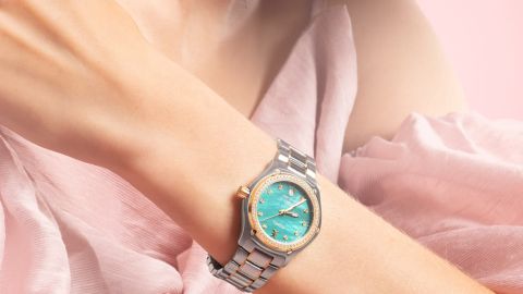 Ebel 1911 Damenuhr mit Gehaeuse aus Stahl und Gelbgold, Diamantluenette, tuerkisfarbenem Perlmuttzifferblatt mit Datum bei 6 Uhr und Bicolorarmband getragen am Handgelenk Ebel 1911 Damenuhr mit Gehaeuse aus Stahl und Gelbgold, Diamantluenette, tuerkisfarbenem Perlmuttzifferblatt mit Datum bei 6 Uhr und Bicolorarmband getragen am Handgelenk