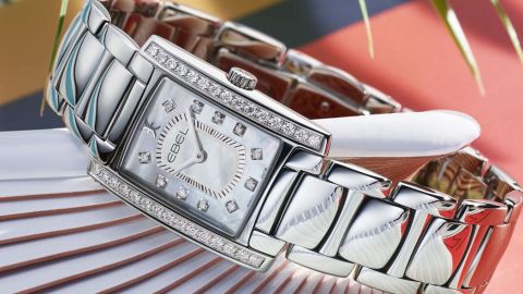 Ebel Brasilia Damenuhr mit Gehaeuse und Band in Stahl Luenette mit Diamanten und Perlmuttzifferblatt mit Diamantindizes seitlich auf farbigem Hintergrund liegend Ebel Brasilia Damenuhr mit Gehaeuse und Band in Stahl Luenette mit Diamanten und Perlmuttzifferblatt mit Diamantindizes seitlich auf farbigem Hintergrund liegend