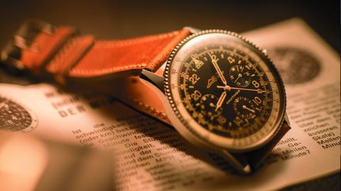 Breitlings ikonische Navitimer Cosmonaute Referenz 809 von 1962 mit braunem Lederarmband auf Flugunterlagen liegend Breitlings ikonische Navitimer Cosmonaute Referenz 809 von 1962 mit braunem Lederarmband auf Flugunterlagen liegend