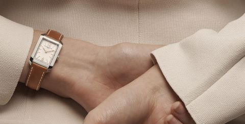 Baume & Mercier Hampton Damenuhr mit eckigem Stahlgehaeuse, hellbraunem Lederarmband und silbernem Zifferblatt an einem Damenhandgelenk getragen Baume & Mercier Hampton Damenuhr mit eckigem Stahlgehaeuse, hellbraunem Lederarmband und silbernem Zifferblatt an einem Damenhandgelenk getragen