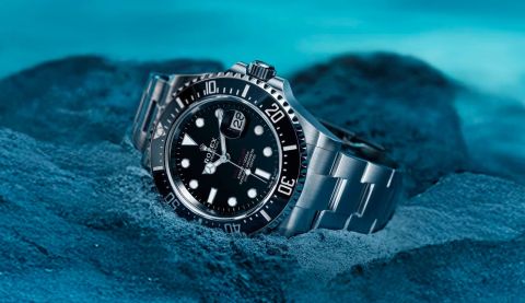 Rolex Sea-Dweller in Edelstahl mit schwarzem Zifferblatt und schwarzer Luenette am Meeresuntergrund liegend