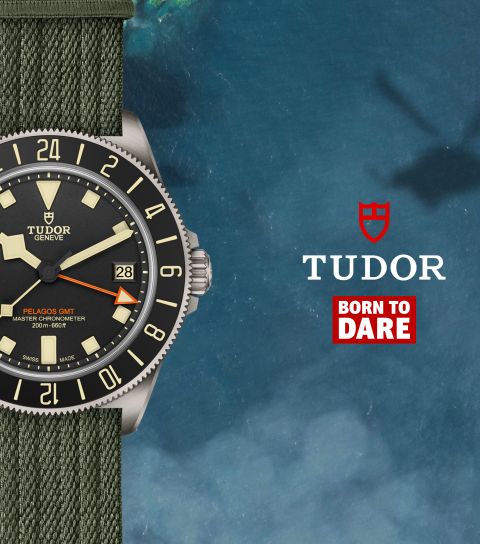 Tudor Pelagos FXD GMT Uhr in Titan mit schwarzer Luenette und Zifferblatt und militarygruenem Textilband vor Wasserhintergrund