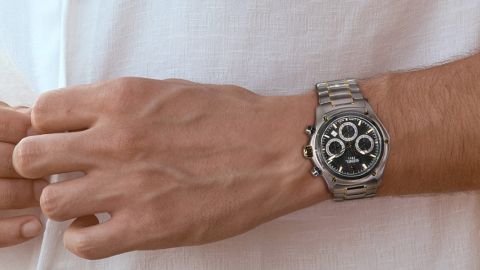 Ebel 1911 Herrenchronograph mit Gehäuse aus Stahl und Gelbgold, schwarzem Zifferblatt und Bicolorarmband getragen am Handgelenk Ebel 1911 Herrenchronograph mit Gehäuse aus Stahl und Gelbgold, schwarzem Zifferblatt und Bicolorarmband getragen am Handgelenk