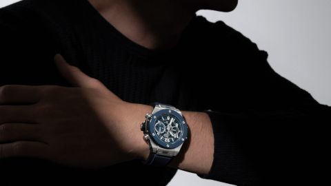Hublot Big Bang Chronograph am Handgelenk eines Mannes in schwarzem Pullover, Nahaufnahme mit dunklem Hintergrund. Hublot Big Bang Chronograph am Handgelenk eines Mannes in schwarzem Pullover, Nahaufnahme mit dunklem Hintergrund.