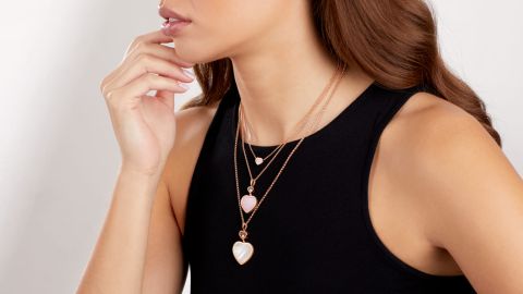 Weibliches Model mit drei Anhaenger aus der Happy Hearts Kollektion an Rosegoldhalsketten, oberer und mittlerer Anhaenger mit rosa Opalherz und unterster mit weissem Perlmuttherz Weibliches Model mit drei Anhaenger aus der Happy Hearts Kollektion an Rosegoldhalsketten, oberer und mittlerer Anhaenger mit rosa Opalherz und unterster mit weissem Perlmuttherz