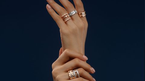 Damenhaende vor blauem Hintergrund, obere Hand mit je einem Ice Cube Ring an Zeige-, Mittel- und Ringfinger in Rose- und Weissgold, untere Hand mit 2 Ice Cube Ringen am Ringfinger