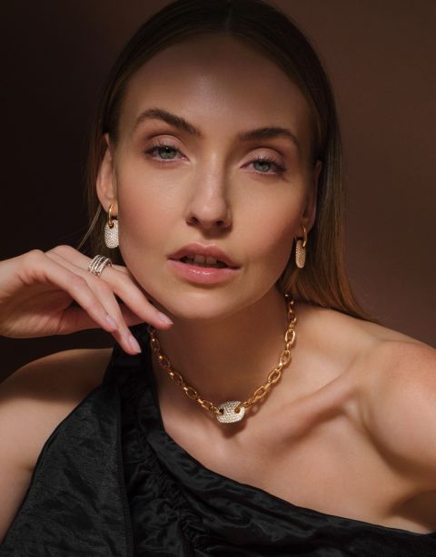 Model trägt goldene Gliederkette mit diamantbesetztem Element, funkelnde Ohrringe und mehrere Ringe aus dem Atelier Mühlbacher und von Crivelli. Model trägt goldene Gliederkette mit diamantbesetztem Element, funkelnde Ohrringe und mehrere Ringe aus dem Atelier Mühlbacher und von Crivelli.