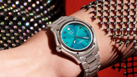 Ebel 1911 Damenuhr mit Stahlgehaeuse, tuerkisfarbenem Zifferblatt mit arabischen Ziffern und Datum bei 6 Uhr und Stahlarmband getragen am Handgelenk Ebel 1911 Damenuhr mit Stahlgehaeuse, tuerkisfarbenem Zifferblatt mit arabischen Ziffern und Datum bei 6 Uhr und Stahlarmband getragen am Handgelenk