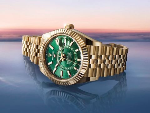 Luxuriöse Rolex Sky-Dweller in Gelbgold mit grünem Zifferblatt vor Sonnenuntergang – exklusive Schweizer Uhr mit automatischem GMT-Uhrwerk und Jubilé-Armband.